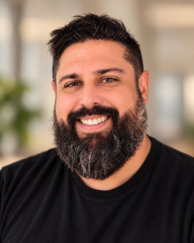 Ryan Witterschein, smiling, with dark hair and a full beard, wearing a black crew-neck shirt.